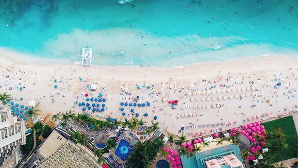An aerial view of a beach with numerous umbrellas, lounge chairs, and a pool area. - OUTRIGGER Waikiki Beach Resort (Honolulu)