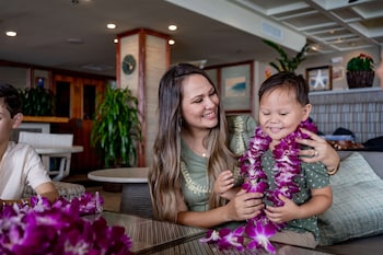 A lobby with a wooden ceiling, a large wall with informational displays, and a traditional canoe on display. at OUTRIGGER Waikiki Beach Resort