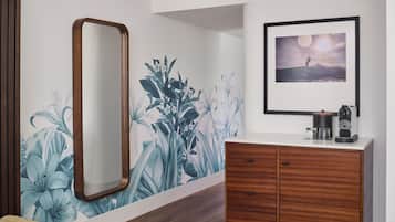 A bedroom with a wooden dresser, a large mirror, a wall mural of flowers, and a framed picture on the wall.