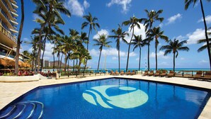 A resort pool with palm trees, lounge chairs, and a view of the ocean. - OUTRIGGER Waikiki Beach Resort (Honolulu)