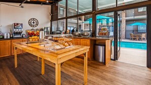 A breakfast buffet area with a wooden table, a coffee machine, and a clock on the wall.