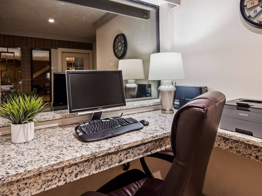 Um espaço de escritório em casa com um computador de mesa, teclado, rato e uma impressora Brother sobre uma bancada de granito.