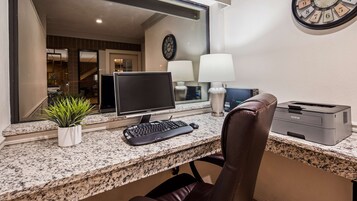 Un espacio de trabajo en casa con una computadora de escritorio, teclado, ratón e impresora Brother sobre una encimera de granito.