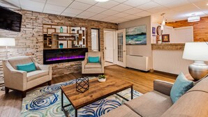 A modern living room with a stone wall, a fireplace, a sofa, a coffee table, and a TV.