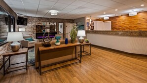 A modern reception area with a wooden reception desk, a fireplace, and a stone wall.