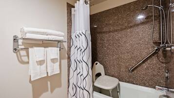Ein Badezimmer mit Dusche, Toilette und Handtuchhalter mit gefalteten Handtüchern.