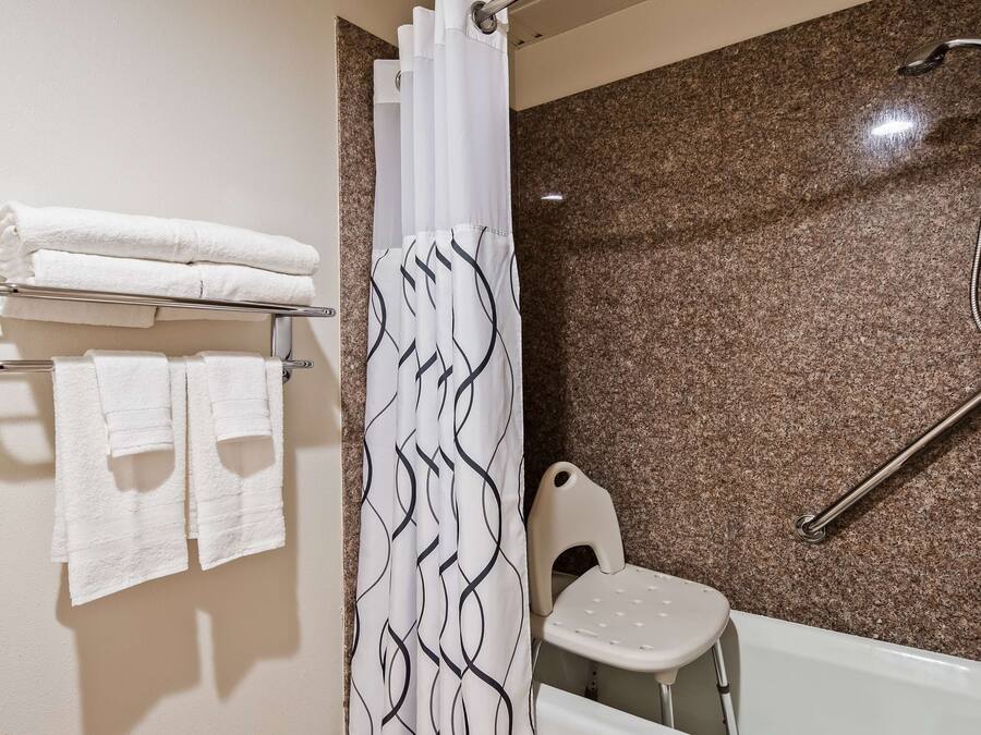 Ein Badezimmer mit Dusche, Toilette und Handtuchhalter mit gefalteten Handtüchern.
