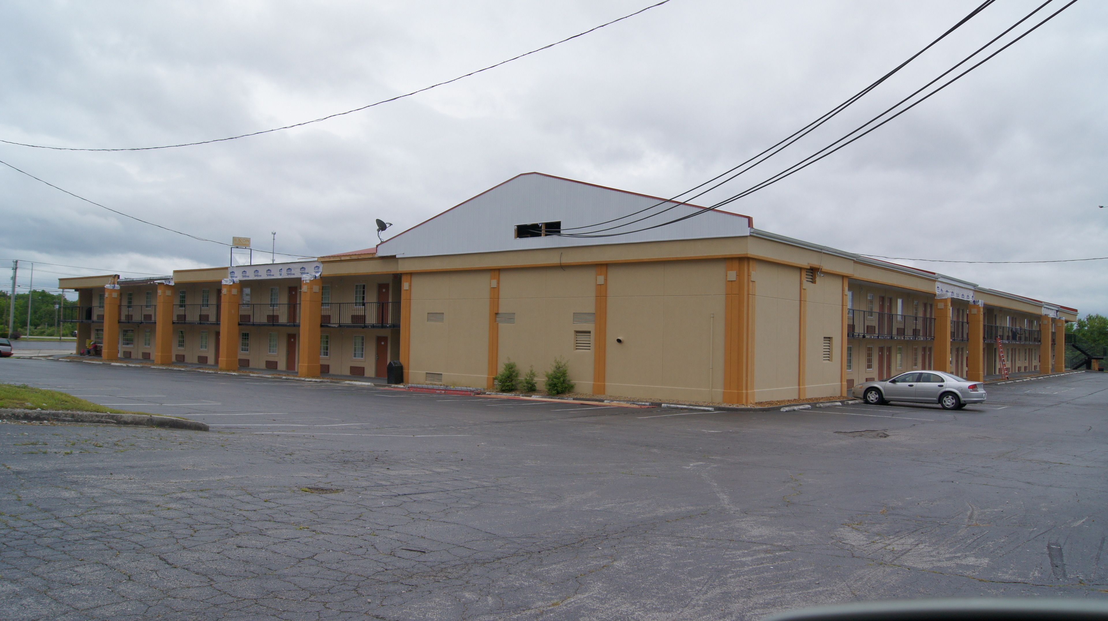A multi-story motel with a flat roof and a parking lot in front.