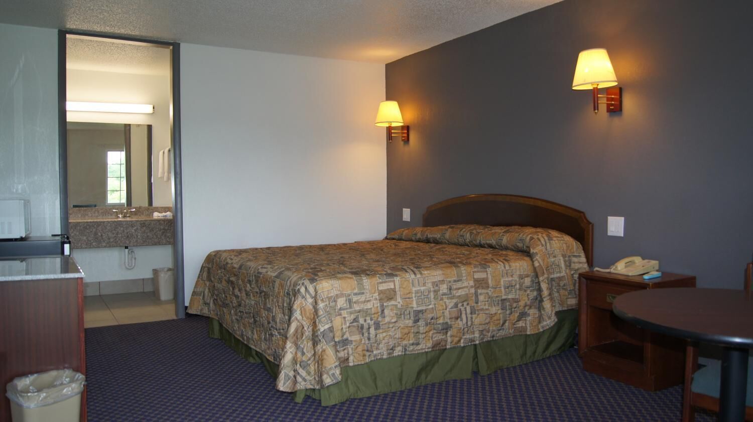Une chambre d’hôtel équipée d’un lit, d’un bureau, d’une chaise, d’une lampe et d’un téléphone.