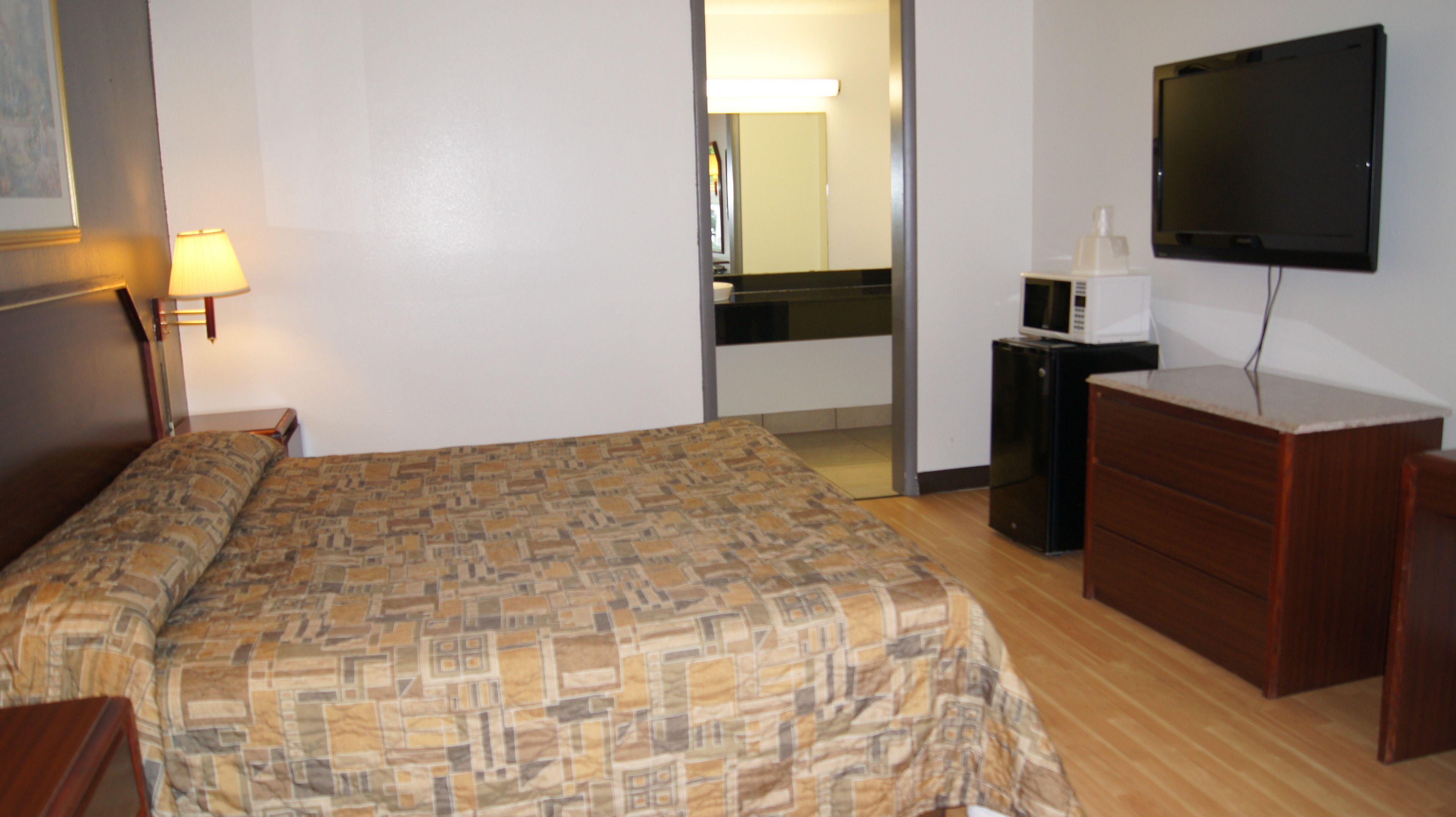 Una habitación de hotel con cama, cómoda, televisión y microondas.