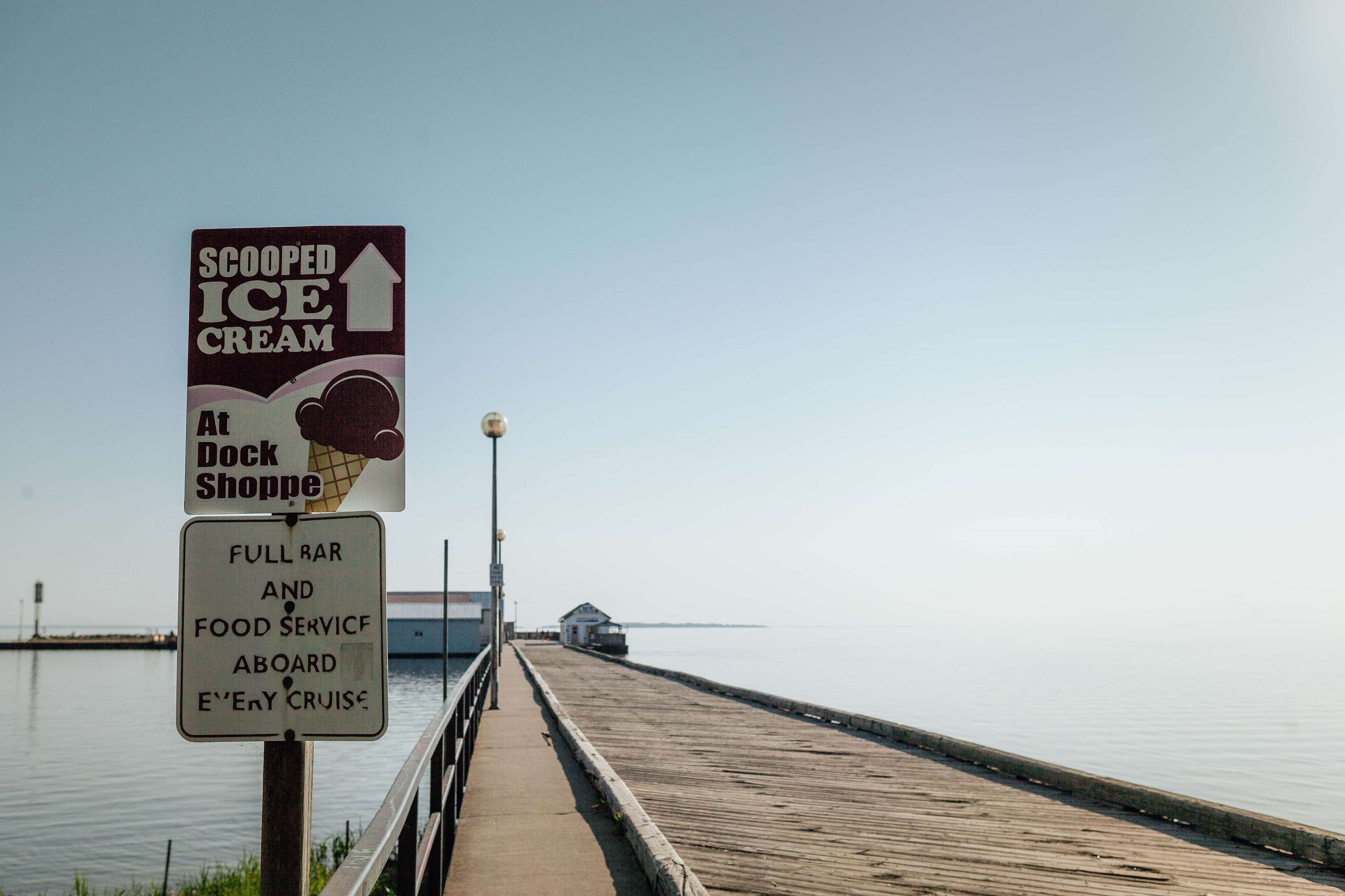 A pier with a sign advertising scooped ice cream and full bar and food service aboard every cruise.