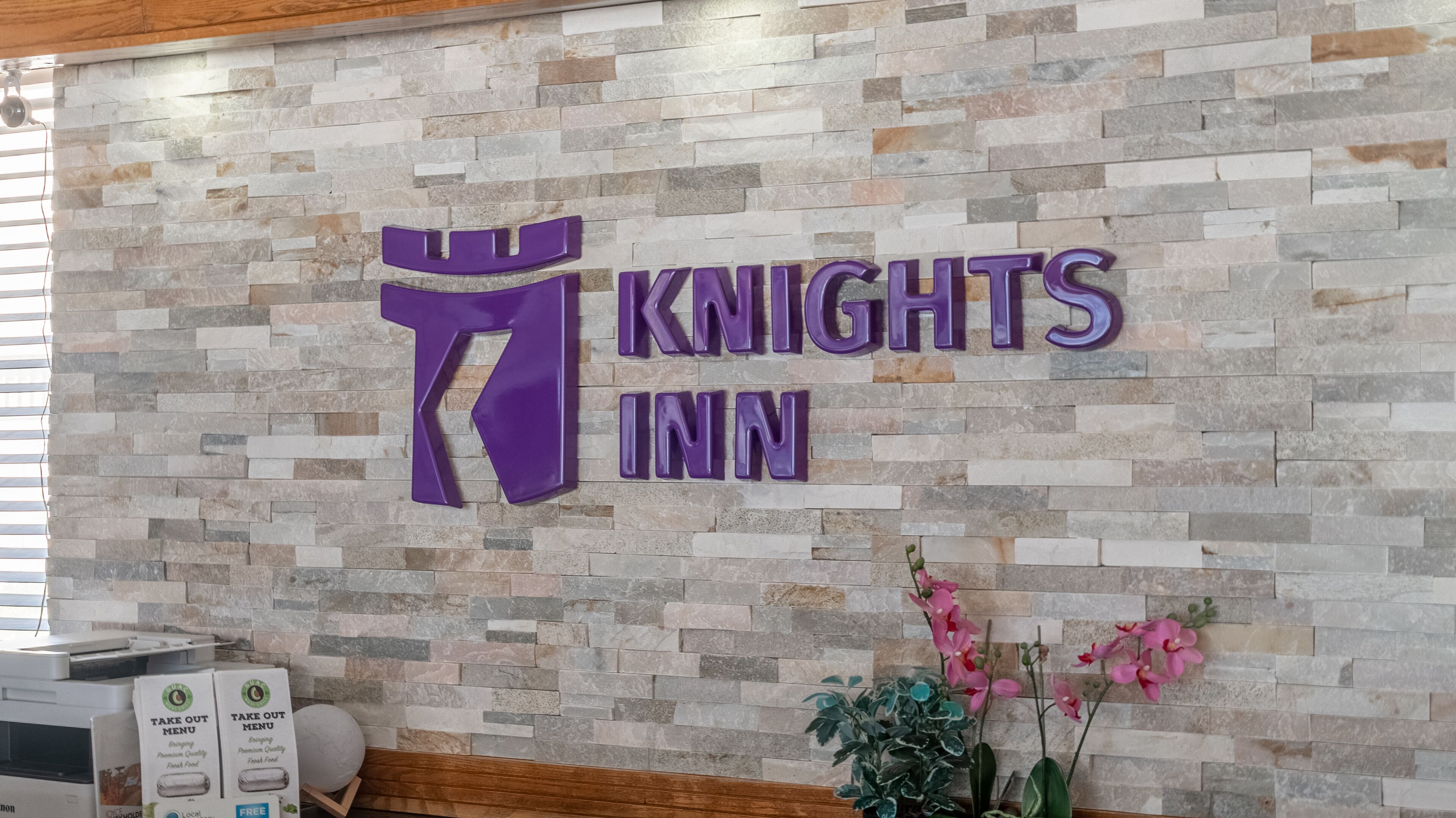 Een receptiegedeelte met een stenen muur en een bord waarop 'Knights Inn' staat.
