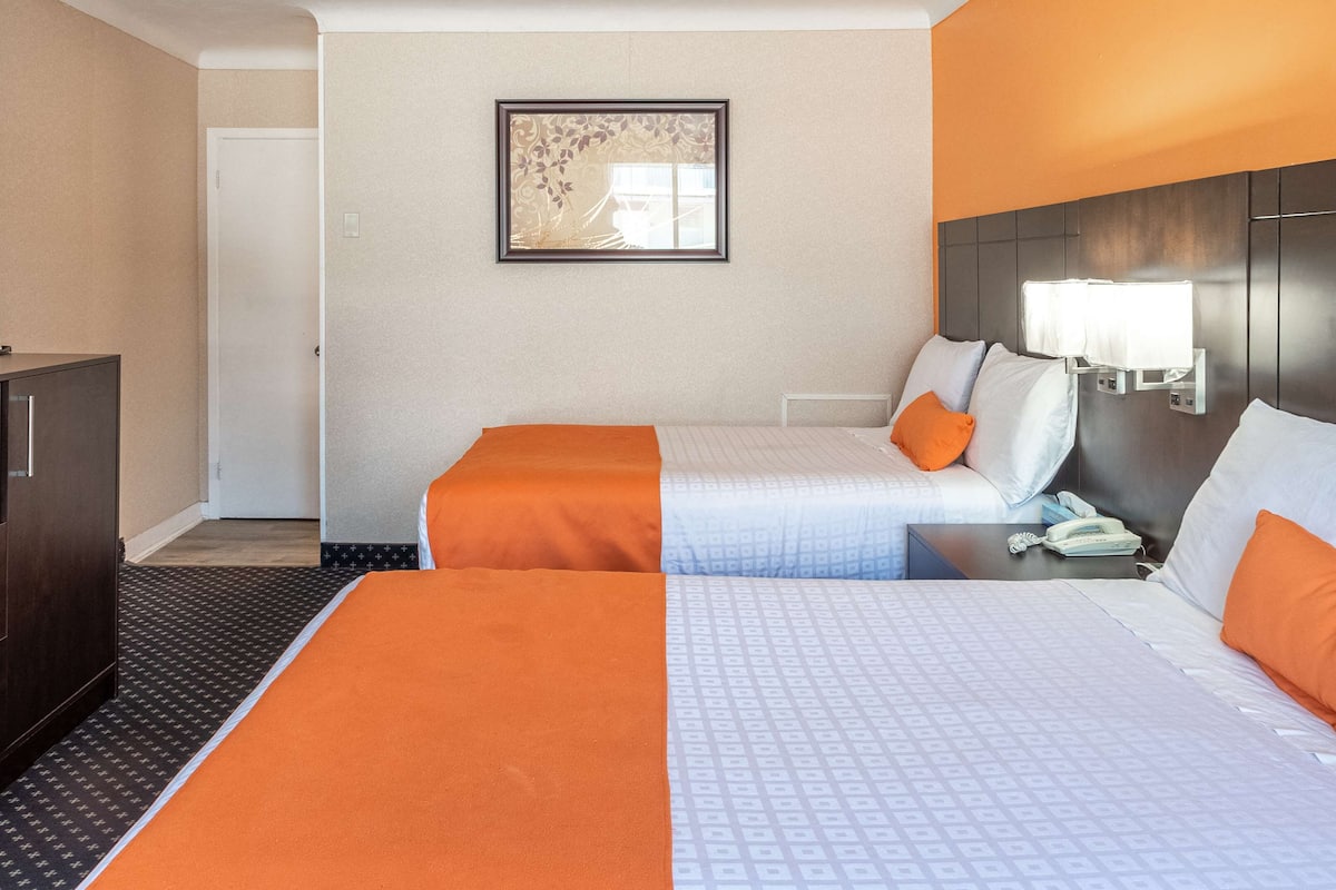 Habitación de hotel con dos camas, una mesita de noche, un teléfono y un cuadro enmarcado en la pared.