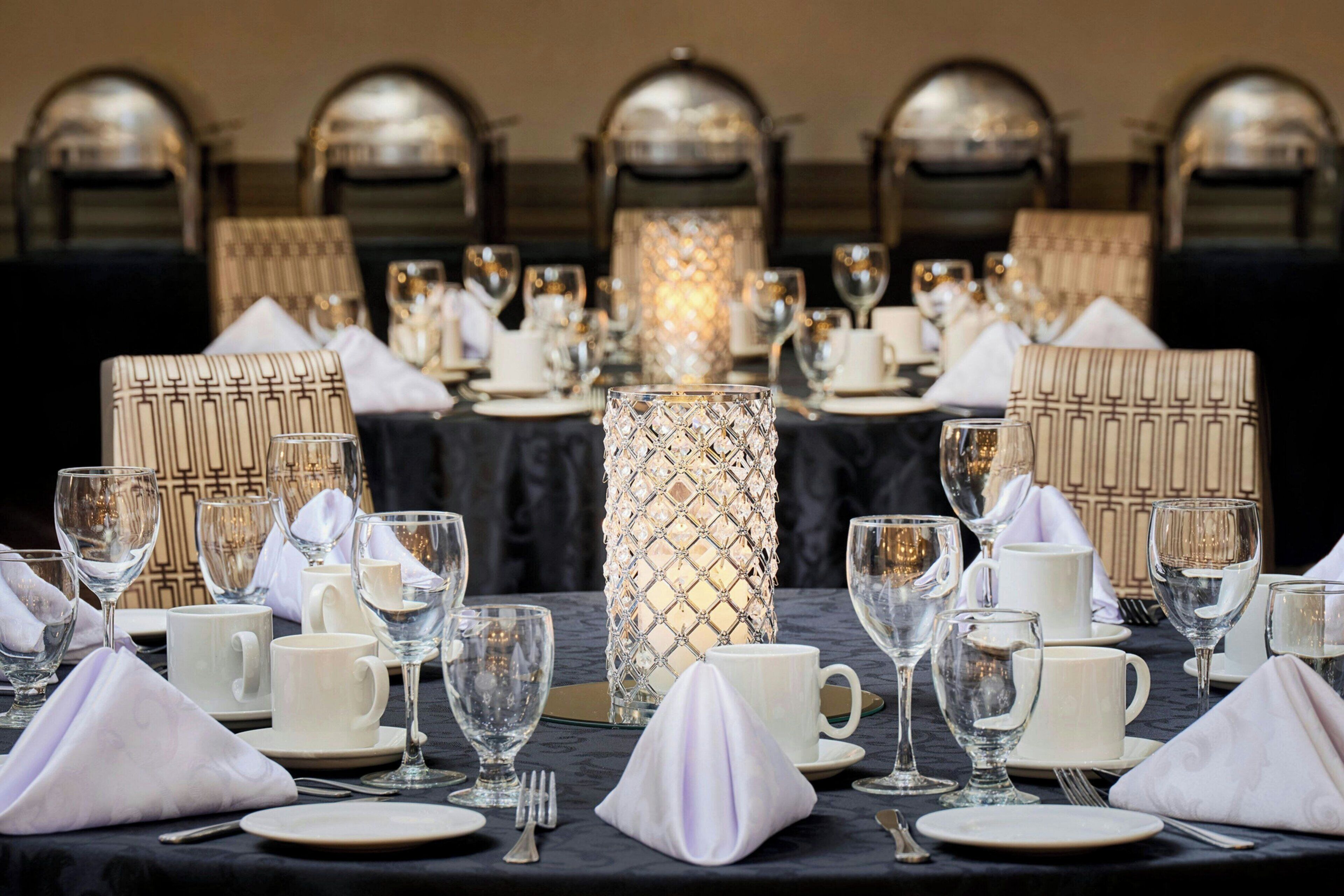 A formal dining table set with white plates, clear glassware, and a decorative candle centerpiece.