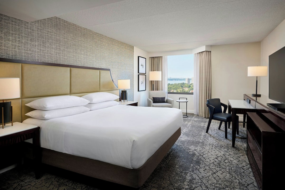 A hotel room with a large bed, a desk, a chair, and a TV.