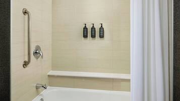 A modern bathroom with a bathtub, a shower, and a handrail.