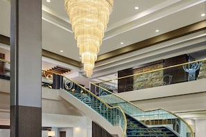 Un intérieur à plusieurs niveaux, agrémenté d’un magnifique lustre, de rampes en verre et d’un escalier moderne.