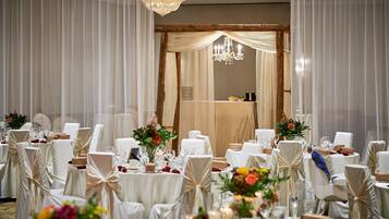 Une salle de banquet avec des tables rondes, des chaises blanches et des centres de table floraux.