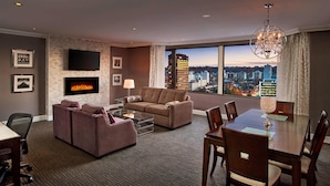 Una habitación de hotel moderna con chimenea, un ventanal con vistas a la ciudad, un televisor de pantalla plana y un comedor.