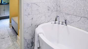 A modern bathroom with a freestanding bathtub, marble walls, and a yellow accent wall.