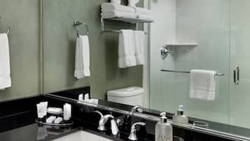 Un baño moderno con un espejo grande, un lavamanos negro y una cabina de ducha de vidrio.