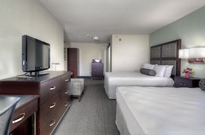 A hotel room with two beds, a desk with a television, a dresser, a small cabinet, and a nightstand with a lamp. - Maple Tree Inn (Sunnyvale)