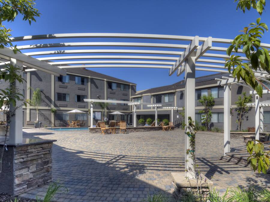 Ein Innenhof mit Pool, Sitzgelegenheiten im Freien und einem überdachten Bereich mit weißen Balken.