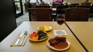 A dining table with a meal consisting of a salad, grilled meat, beans, and a glass of red wine. - Maple Tree Inn (Sunnyvale)