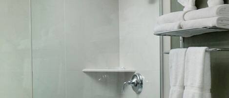 Un baño moderno con cabina de ducha de vidrio, puerta de cristal, toallero con toallas y un inodoro.