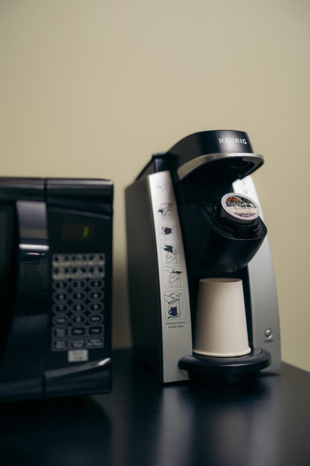 Uma máquina de café Keurig com um recipiente de café e uma cafeteira preta.