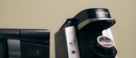 Uma máquina de café Keurig com um recipiente de café e uma cafeteira preta.