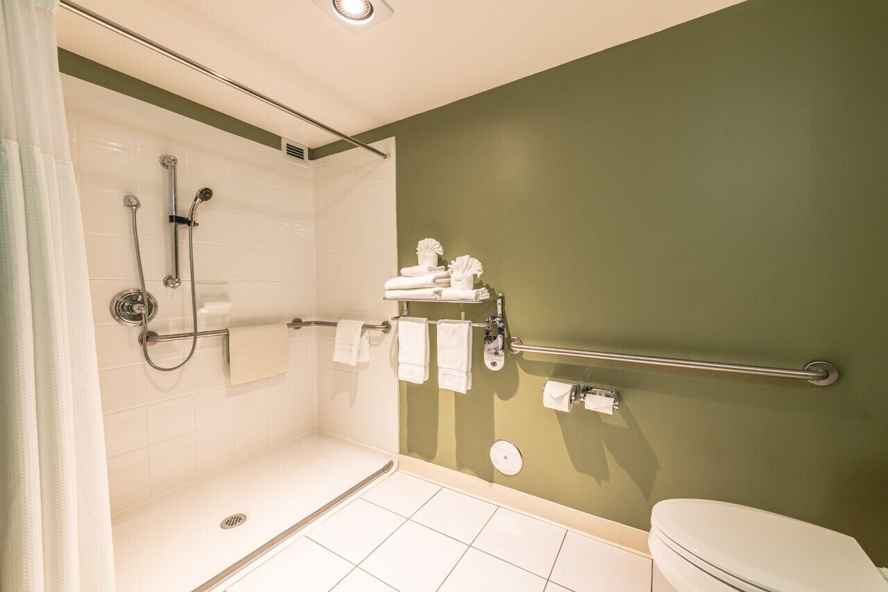 Een badkamer met douche, toilet en handdoekrek.