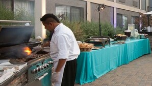 A chef cooking outdoors with a grill and buffet setup. - Maple Tree Inn (Sunnyvale)