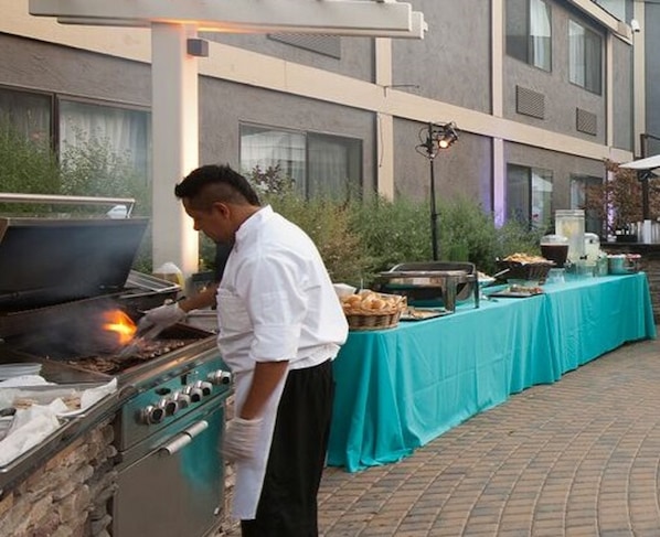 A chef cooking outdoors with a grill and buffet setup. - Maple Tree Inn (Sunnyvale)