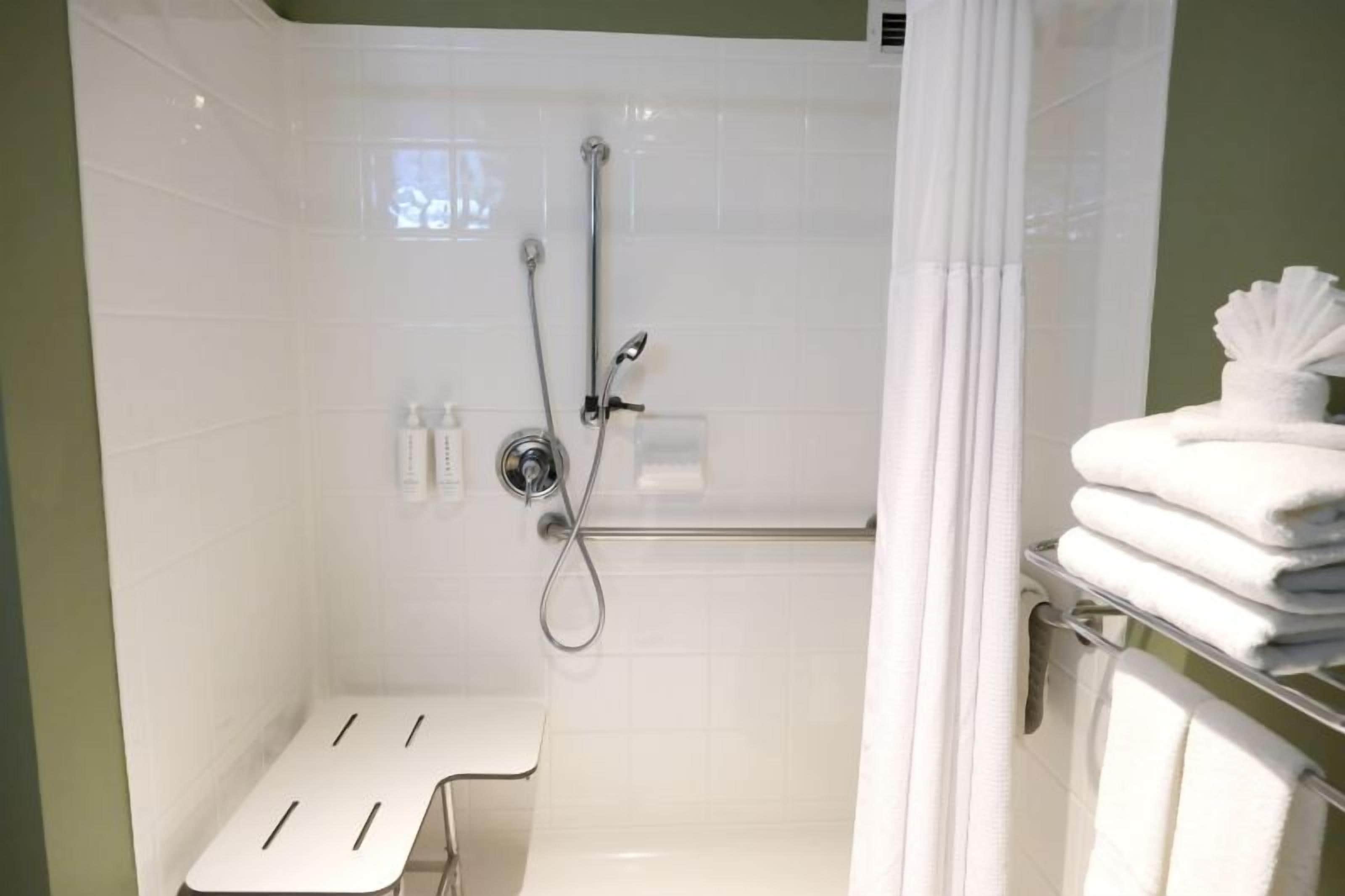 Un baño con ducha, un banco y un perchero.