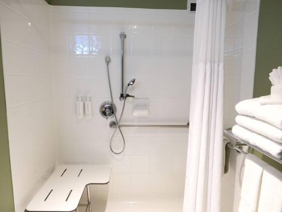 A bathroom with a shower, a bench, and a towel rack.