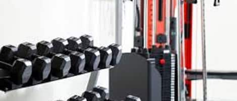 A row of black dumbbells on a rack in a gym setting.