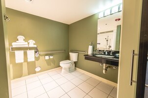 Un baño con inodoro, lavamanos y barras de apoyo.
