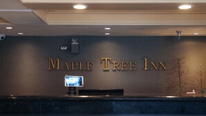 A reception desk with the name 'Maple Tree Inn' in gold lettering on the wall. - Maple Tree Inn (Sunnyvale)