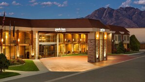 Un hotel Park Inn con una estructura de dos pisos, amplios ventanales de vidrio y una entrada bien iluminada.