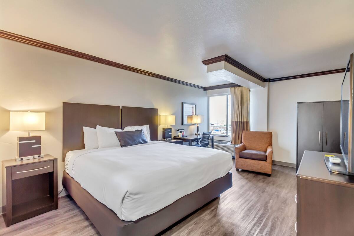 Ein Hotelzimmer mit einem großen Bett, Nachttischen, einem Schreibtisch, einem Stuhl und einem Kleiderschrank.