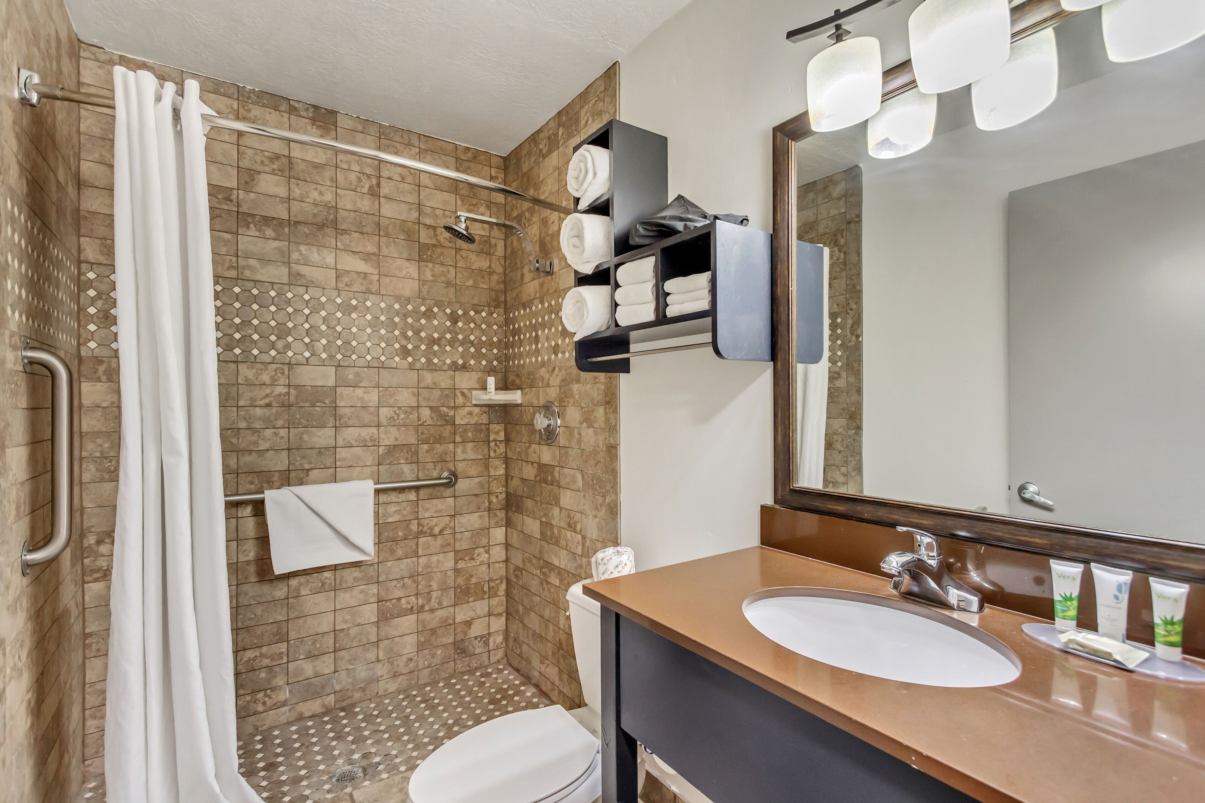 A modern bathroom with a shower, toilet, and sink.