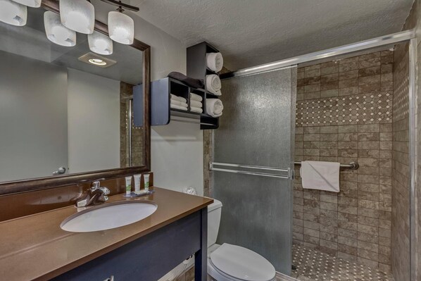 Un baño con lavamanos, espejo, toallero y cabina de ducha.