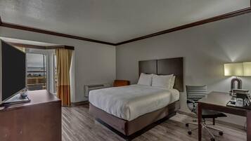 A hotel room with a large bed, a desk, a chair, and a TV.