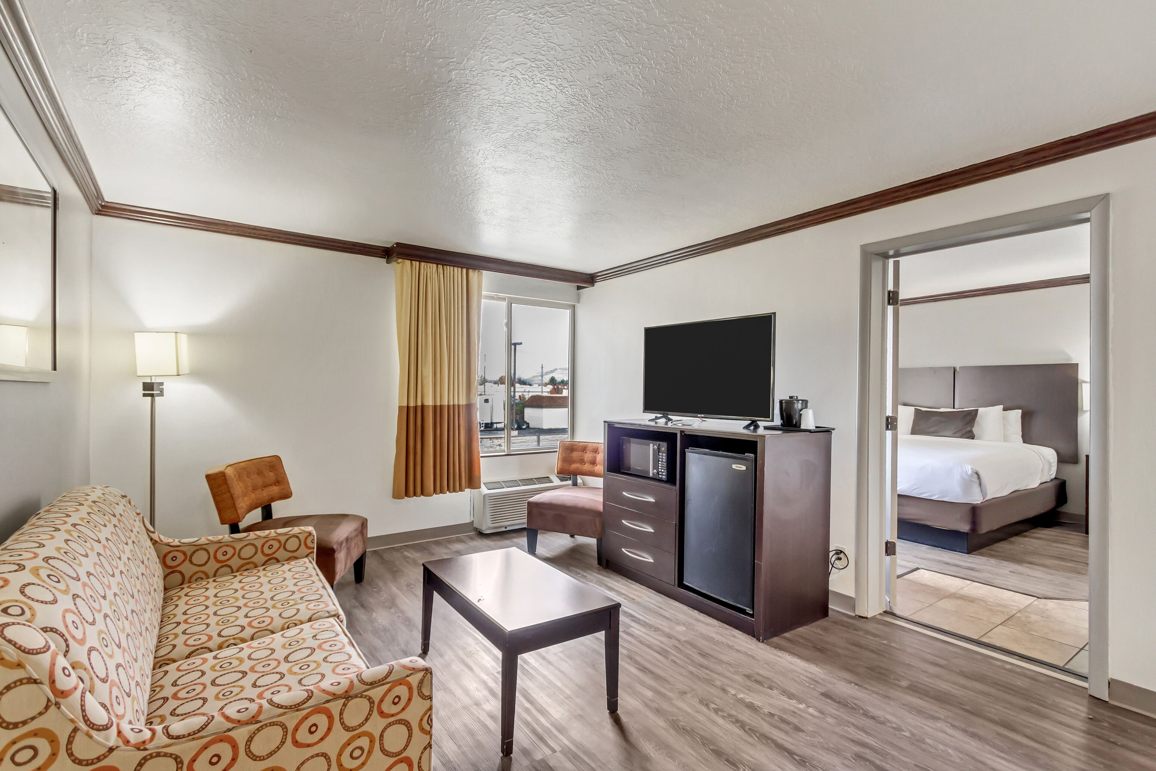 Una habitación de hotel con sofá, una pequeña mesa, televisor, minibar y cama.