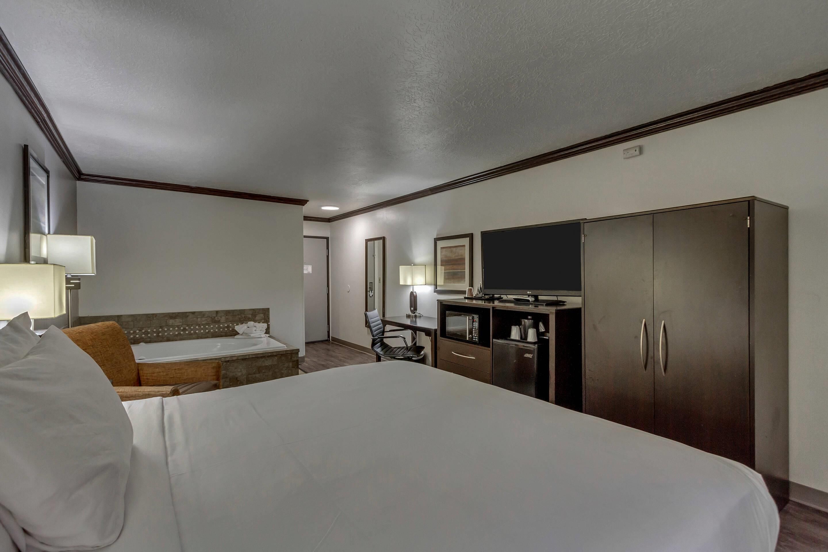 Una camera d'albergo con un letto, una scrivania, una televisione e un armadio.
