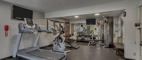Ein Fitnessstudio mit Laufbändern, Crosstrainern und Gewichten.