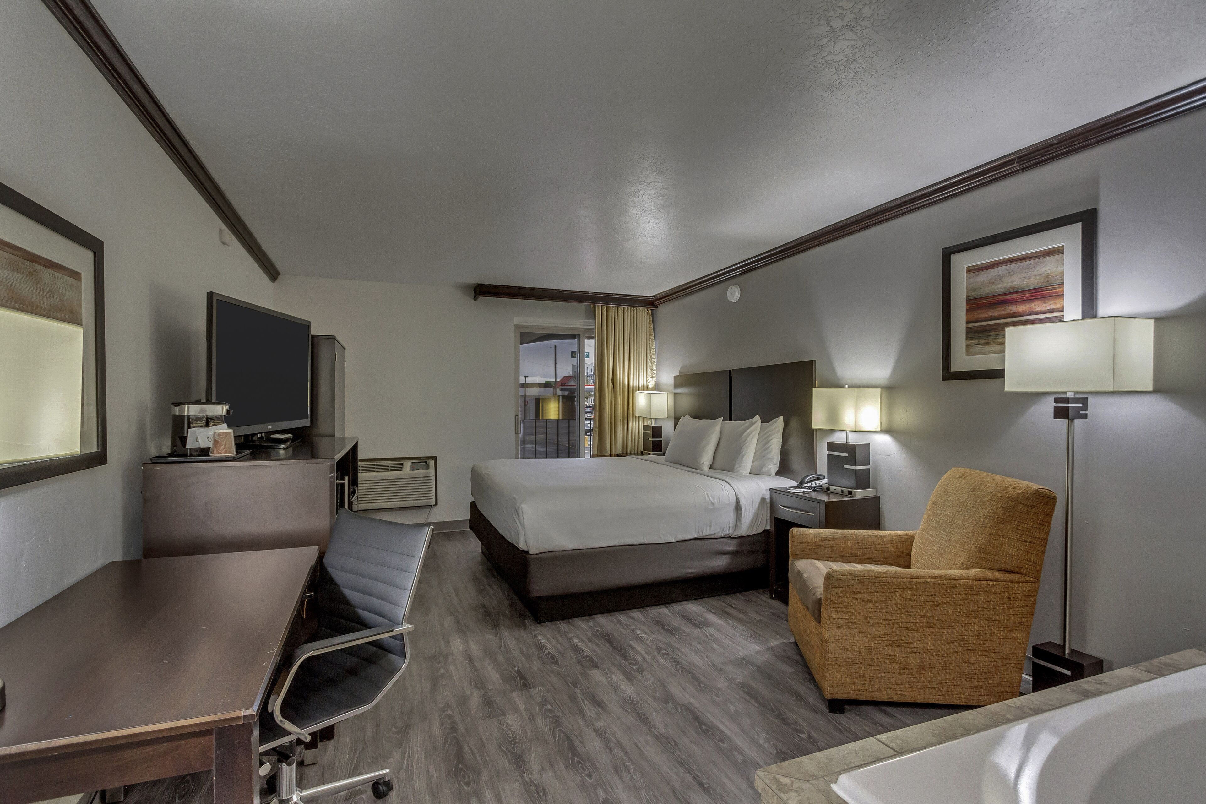 Ein Hotelzimmer mit Bett, Schreibtisch, Stuhl, Lampe und Fernseher.
