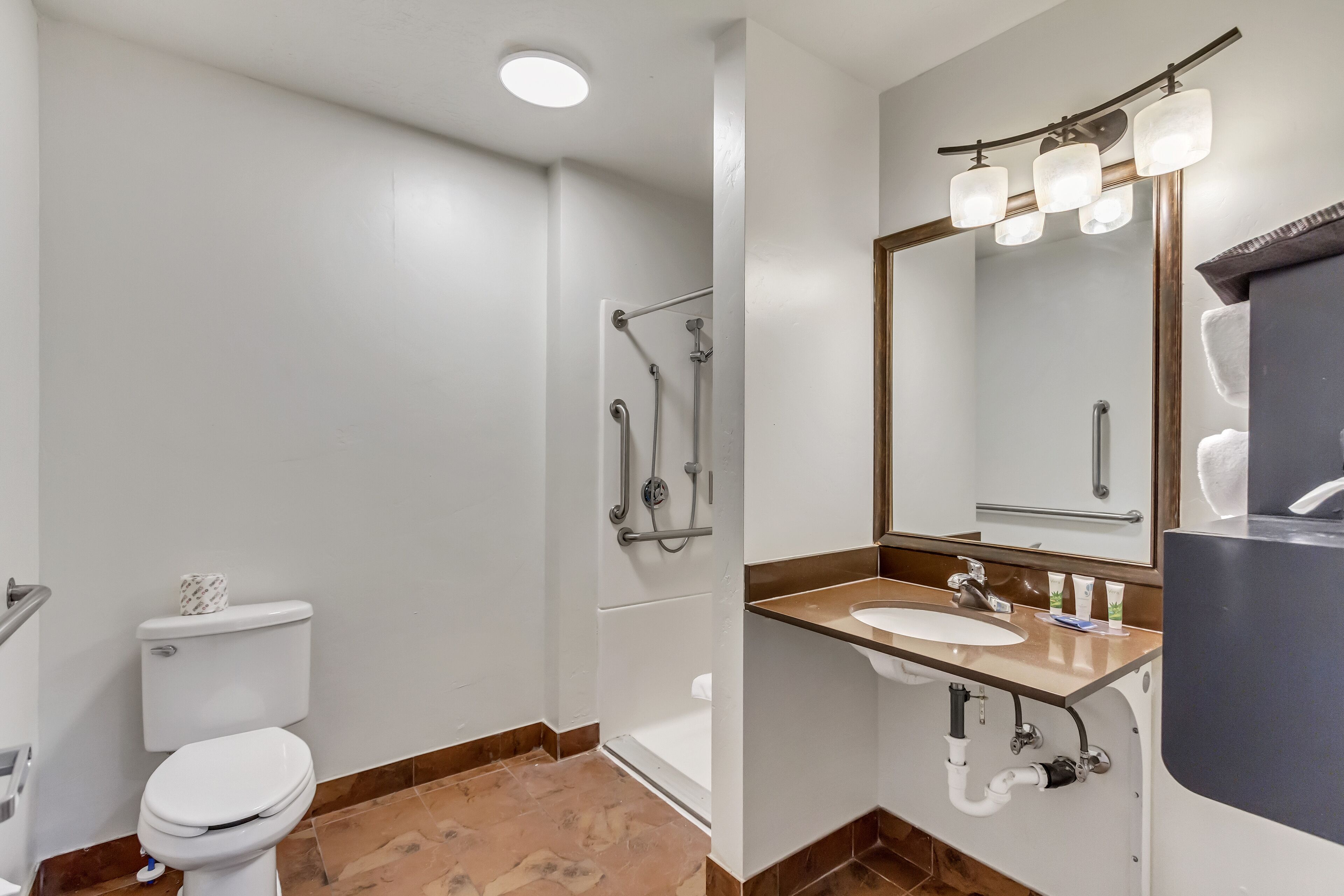 Une salle de bain moderne équipée de toilettes, d’une douche, d’un lavabo et d’un miroir.