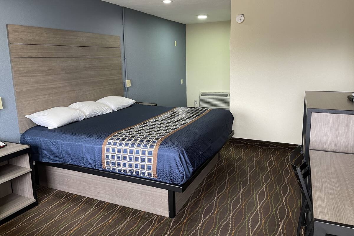 A hotel room with a bed, a desk, and a chair.